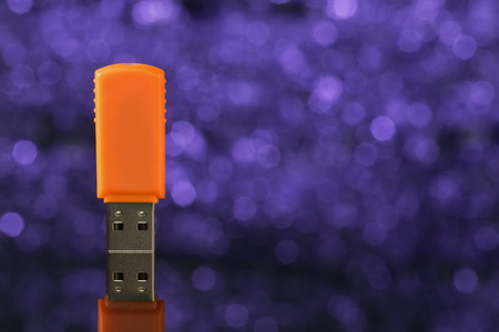 Orange USB flash drive on violet background out of focus. Front viewの写真素材