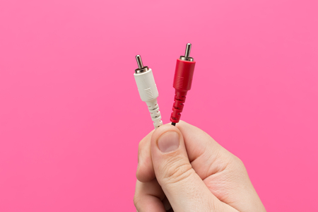 RCA Cables in Hand. Pink background and seen from front