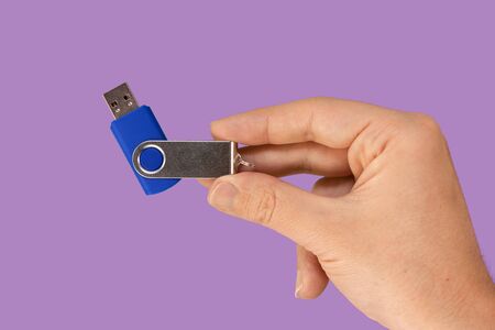 Blue USB flash memory on hand with isolated violet background. Front view
