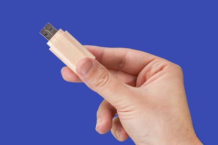 Wood USB pen drive on hand with isolated blue background. Front viewの写真素材
