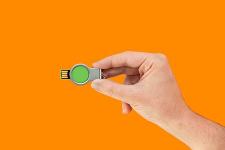 Green flash memory on hand with isolated orange background. Front viewの写真素材