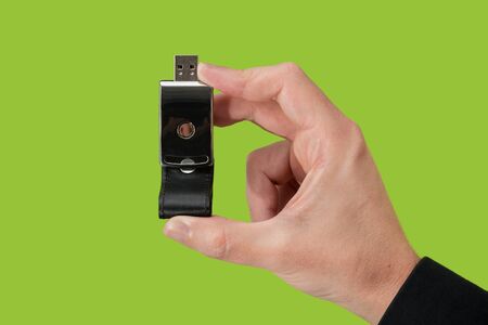 Dark pen drive on hand with isolated green background. Front viewの写真素材