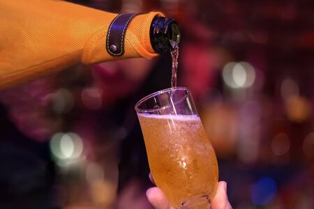 Serving a glass of champagne to the client. Close-up of bottle and glassの写真素材