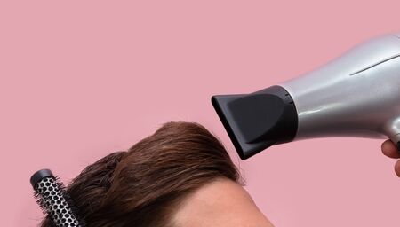 Hairdresser cutting combing and drying a man's hair. Flesh coloured backgroundの写真素材