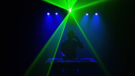 DJ - Silhouette of the man Disc jockey . Disco lights and laser. Blue and green lightingの写真素材