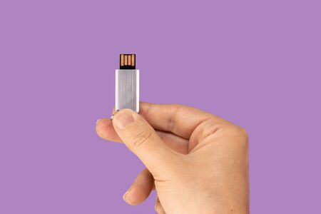 Gray flash drive on hand with isolated violet background. Front viewの写真素材