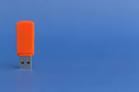 Orange USB flash drive on blue background. Close-upの写真素材