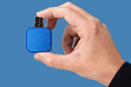 Blue flash drive on hand with isolated blue background. Front viewの写真素材