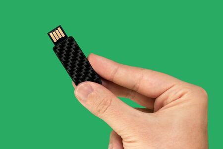 Black pen drive on hand with isolated green background. Front viewの写真素材