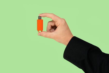 Orange USB pen drive on hand with isolated green background. Front viewの写真素材