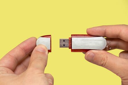 Red flash drive on hand with isolated yellow background. Front viewの写真素材