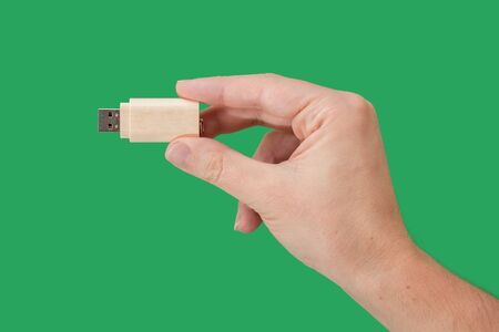 Wood USB memory stick on hand with green background. Front viewの写真素材