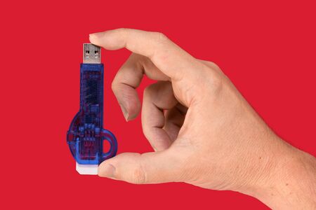 Blue USB Flash drive on hand with isolated red background. Front viewの写真素材