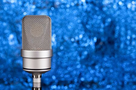 Mic - Close-up of a professional gray large-diaphragm condenser microphone. Blue background with no focusの写真素材