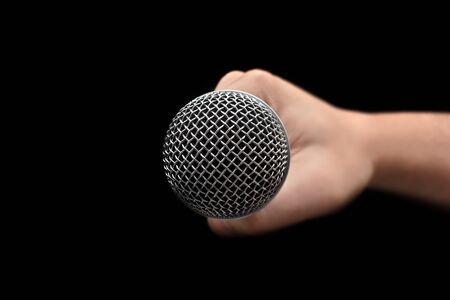 Mic - Close-up of the dynamic microphone held with one hand on an isolated black background. Professional Systemの写真素材