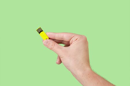 Yellow memory stick on hand with green background. Front viewの写真素材
