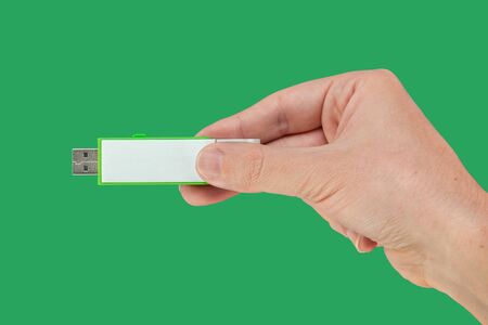 Green pen drive on hand with isolated green background. Front viewの写真素材