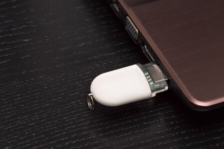 USB memory stick - White flash drive connected to a laptop. Viewed from close up