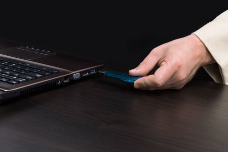 USB memory stick - Flash drive in hand by connecting it to a laptop. Wearing a light colored jacketの写真素材