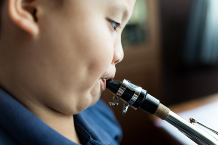 kid practises saxophone with close up blowing actionの写真素材