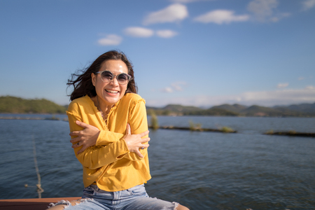 Asian woman smiles happily at lakeside, environmental portraitの写真素材