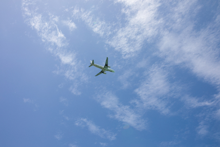 Civilian airplane flying across blue skyの写真素材