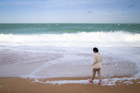 Asian woman thinking and walking on the beach in sunshine day