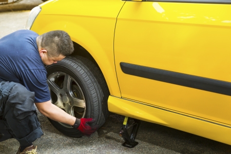 An Asian mechanic changing a car tire.の写真素材