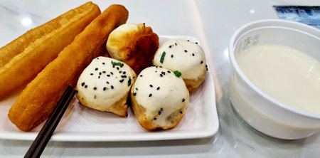 Sweetmeat in white plate with cup of milk on tableの写真素材