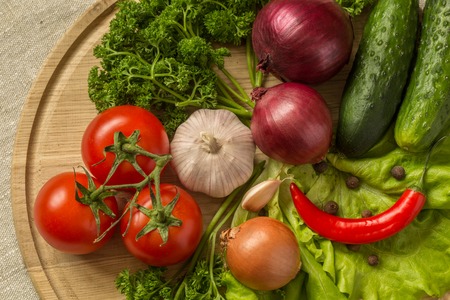 raw vegetables on a round wooden Board. top view.