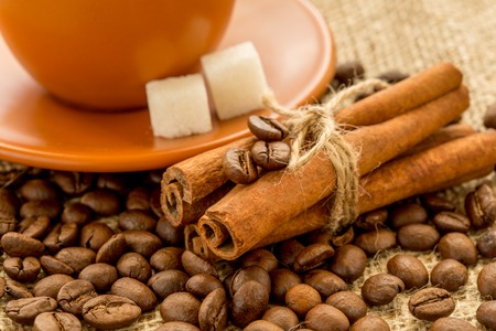 Cup of coffee on burlap background. coffee beans, cinnamon sticks, sugar cubes and star aniseの写真素材
