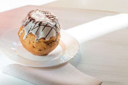Rum baba cake on a white plate on a wooden tableの写真素材