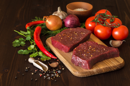 raw beef steak with ingredients for cooking on wooden Boardsの写真素材