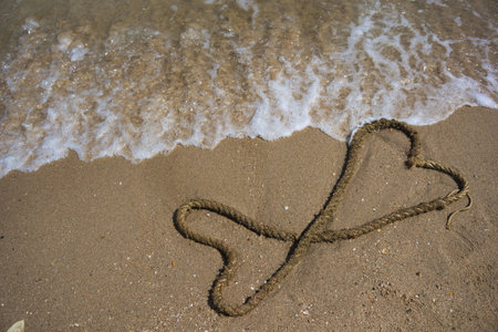 Hemp rope is arranged in a heart shape on the beach.の写真素材