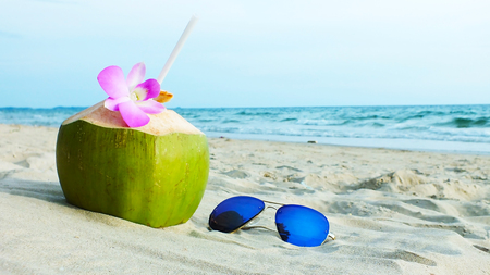 A coconut and a sunglasses on a beach In the holidays.の写真素材