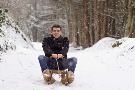 Man riding a sleigh, having fun and laughing - Winter time & sledge funの写真素材