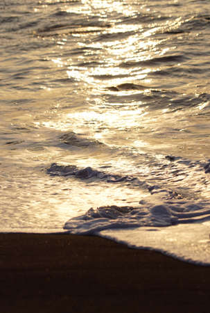 golden sea ripple, details of shiny water at the beach during sunsetの写真素材