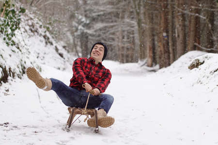 Man fooling around on a sleigh and making a crazy face - having fun on the sledgeの写真素材