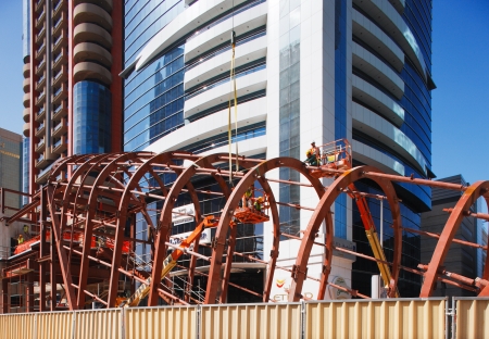 Cherry-pickers are used to hoist the man into position safely in order to assemble and bolt the steel together of the Dubai Metro Stationのeditorial素材