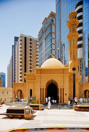 Prayer time at the Friday Mosque in Abu Dhabi, note the contrast in architecture where a contemporary skyscraper towers over a traditional mosqueのeditorial素材