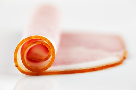 A slice of organic ham, partially rolled and shot against a white backgroundの写真素材