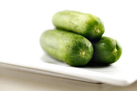 Organic cucumbers on a white ceramic plate and shot against a white backgroundの写真素材