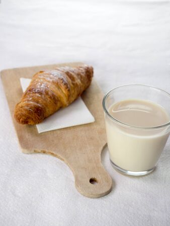 Glass of milk and a croissant, we have a light backgroundの写真素材