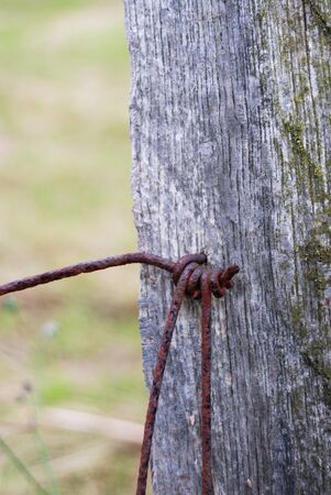 Rusty metallic wire on a fence in rural fieldの写真素材
