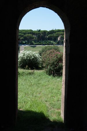 Palatine hill landscape with flowers and trees through the opening of a door. Old Roman Historical Architecture. Palatino Romaの写真素材