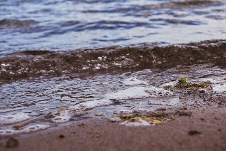 Details of rocks and sand on a lake with small wavesの写真素材