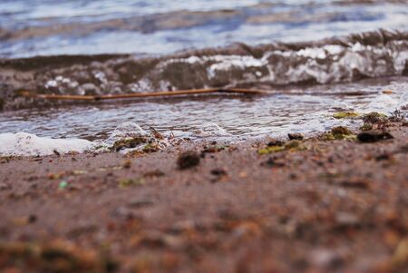 Details of rocks and sand on a lake with small wavesの写真素材