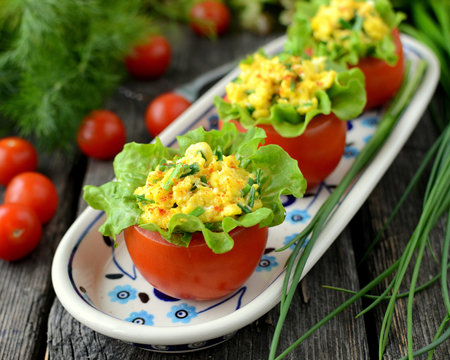 Tomatoes stuffed with scrambled eggs and garnished with a lettuce leaf.の写真素材