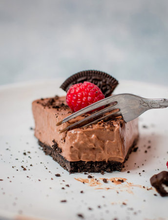 Tart sprinkled with ground chocolate stuffed with mousse  topped with raspberry and a piece of...