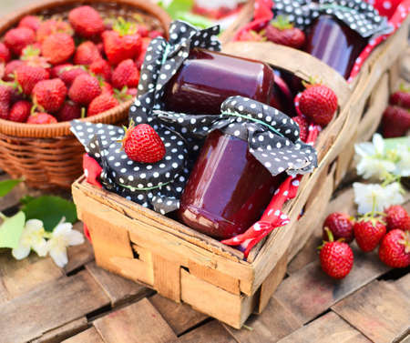 Fresh homemade strawberry jam packed in a garden basket. Summer composition, saturated with colors.の写真素材